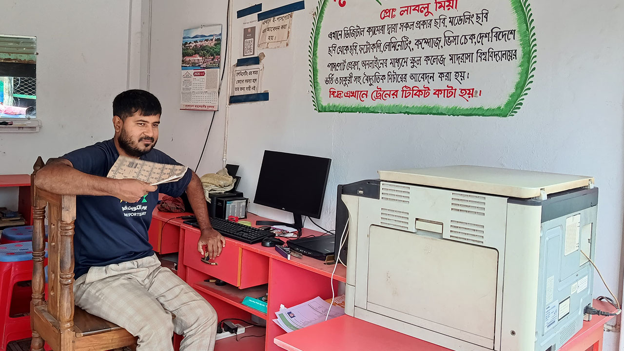 বিদ্যুৎ না থাকায় দোকানে অলস সময় কাটাচ্ছেন ফটোস্ট্যাট ও কম্পিউটার ব্যবসায়ী লাবলু মিয়া। ছবি : এশিয়া পোস্ট