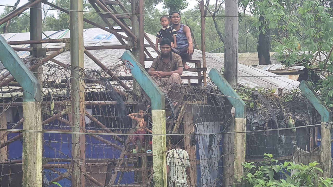 আশ্রয় শিবিরের বেড়ার ওপর বসে আছেন রোহিঙ্গারা। ছবি: এশিয়া পোস্ট
